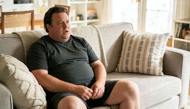 Middle-aged man sitting on sofa talking, casual home lifestyle, cozy living room scene