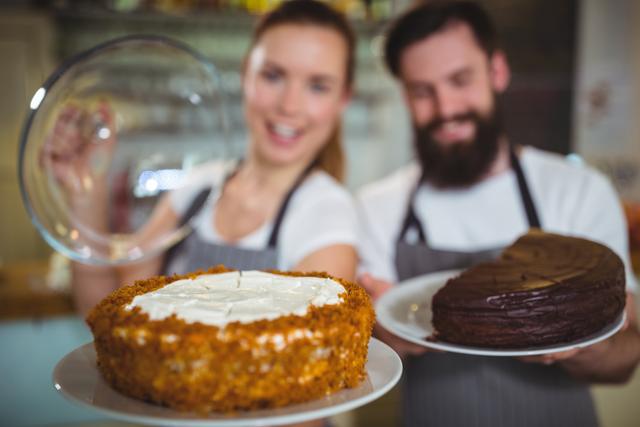Waitstaff in a cafe presenting two different cakes, one with white frosting and the other with chocolate. Ideal for use in advertisements for bakeries, cafes, and restaurants, or in articles about hospitality and customer service.