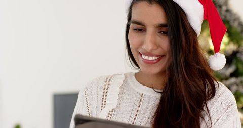 Woman in Santa Hat Using Tablet by Christmas Tree at Home