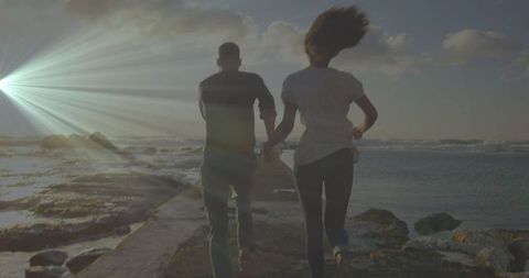 Couple running on jetty at sunset in scenic beach atmosphere