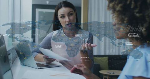 Professional Women Collaborating with Futuristic Holographic World Map