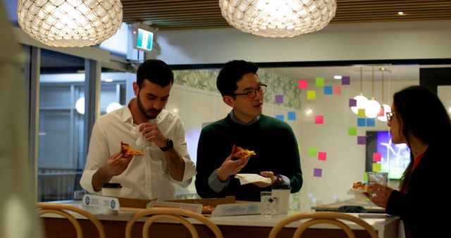Office workers gathering in a break room enjoying pizza together. Bright, corporate environment with a casual, friendly atmosphere. Ideal for illustrating corporate culture, team building activities, or workplace social settings.