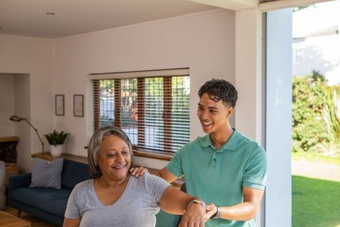 Son Assists Senior Mother with Stretching at Home