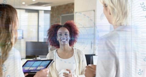 Smiling woman holding coffee and talking with colleagues in modern office collaboration