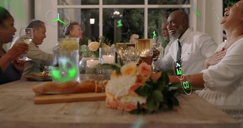 Multigenerational group toasting around candlelit wooden table laughing and celebrating
