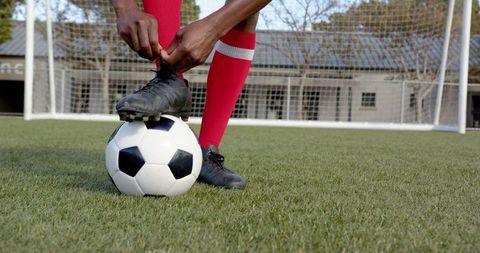 Soccer Player Tying Cleats Preparing for Game on Field