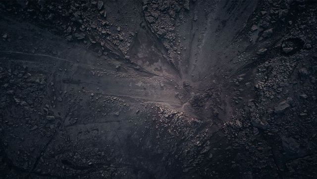 Aerial view barren rocky crater with radial erosion channels and vehicle ruts