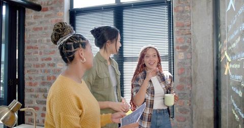 Team Brainstorming Session Around Glass Board in Modern Office