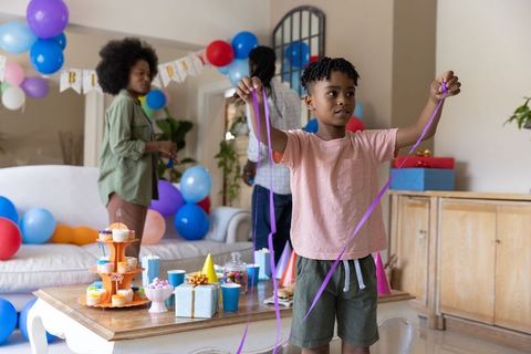 African american family decorating living room for kids birthday with balloons and cupcakes