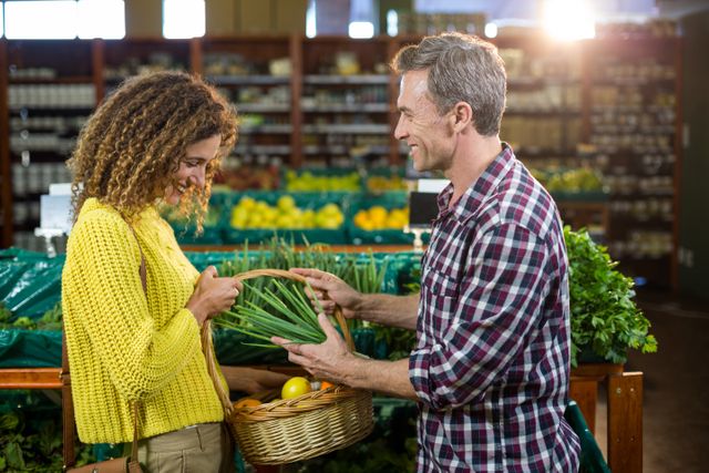 Happy couple buying vegetables in organic section of supermarket