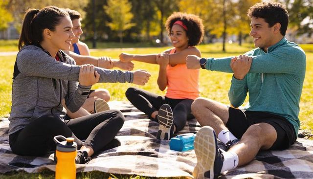 Group stretching and outdoor fitness on checkered blanket, friends exercising and smiling together