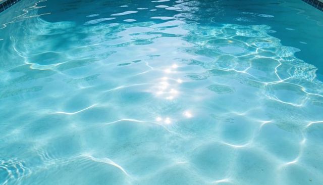 Sunlit turquoise swimming pool water with shimmering caustics and gentle ripples