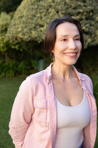 Confident Woman Smiling Outdoors in Tranquil Garden Scene