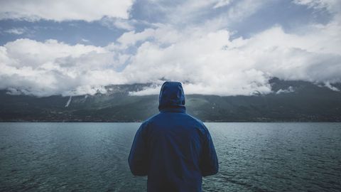 Solitary Person in Blue Coat Overlooking Lake and Mountains