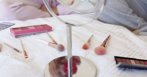 Relaxing morning makeup routine with round mirror, brushes and eyeshadow palettes