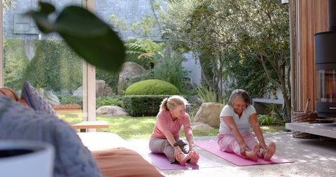 Mother and Daughter Stretching in Sunlit Modern Room Opening to Garden