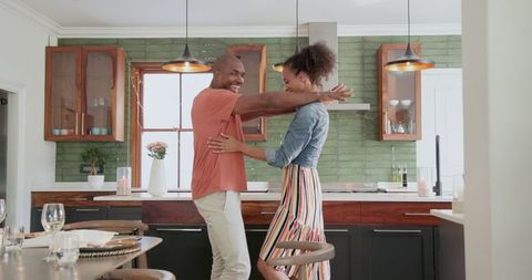Joyful couple dancing in modern kitchen for a moment of celebration