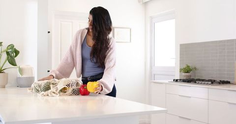 Eco-conscious woman unpacking vegetables in minimalist kitchen