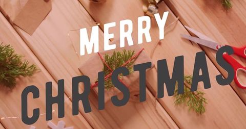 Merry Christmas kraft gift flatlay with twine, evergreen sprigs and red scissors on wood