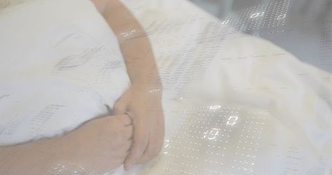 Clasping couple hands resting on white bed linens with soft dotted light projection