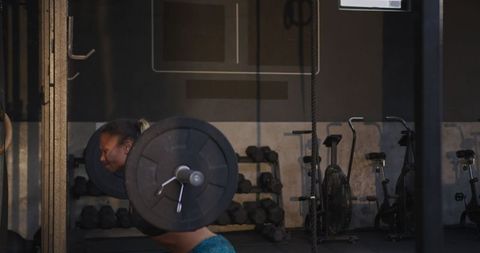 Athletic Woman Strength Training with Barbell in Gym