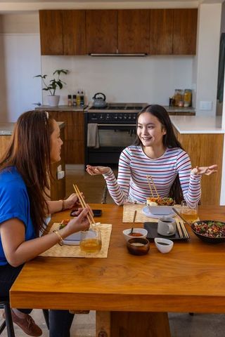 Mother and Daughter Enjoying Meal Together at Home Kitchen