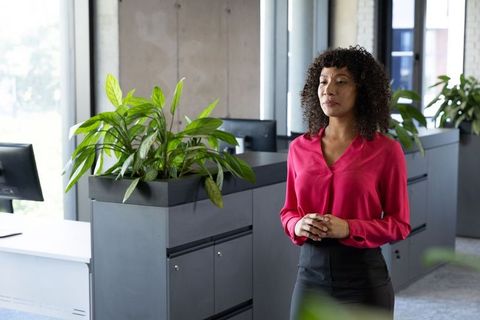 Professional Woman Contemplating in Modern Office with Greenery