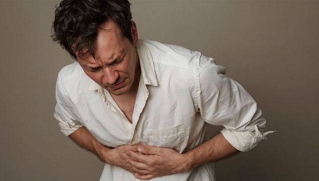 Man clutching chest and wincing from acute chest pain conveying sudden medical distress