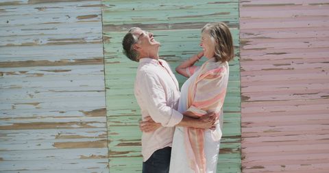 Happy Senior Couple Embracing Against Colorful Wooden Wall - Download Free Stock Images Pikwizard.com