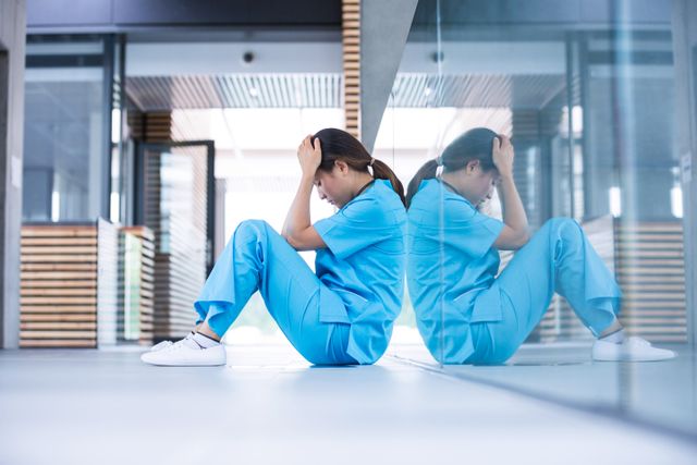 Stressed nurse sitting in hospital corridor