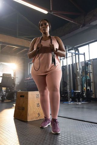 African american woman exercising in pink activewear holding jump rope by plyo box