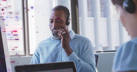 Customer support agent speaking on headset while working at laptop in modern office
