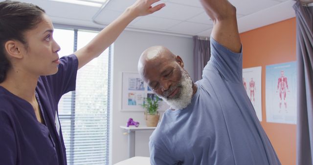 Elderly man engages in stretching exercise under guidance of physical therapist in modern clinic. Perfect for use in promotional materials for healthcare services, physical therapy centers, and wellness programs. Also suitable for illustrating articles on senior health, physical exercise, and rehabilitation processes.