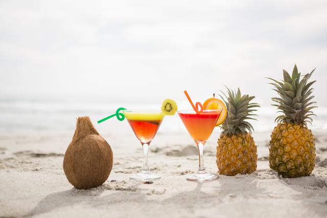 Tropical cocktails and fresh fruits on sandy beach. Ideal for promoting summer vacations, beach resorts, tropical drinks, and relaxation. Perfect for travel brochures, holiday advertisements, and social media posts about beach getaways.