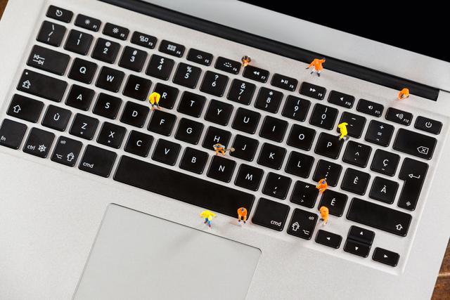 Conceptual image of miniature workmen repairing laptop keyboard showcasing technology maintenance and IT support. Ideal for creative tech presentations, IT services advertisements, and educational materials on computer maintenance and repair.