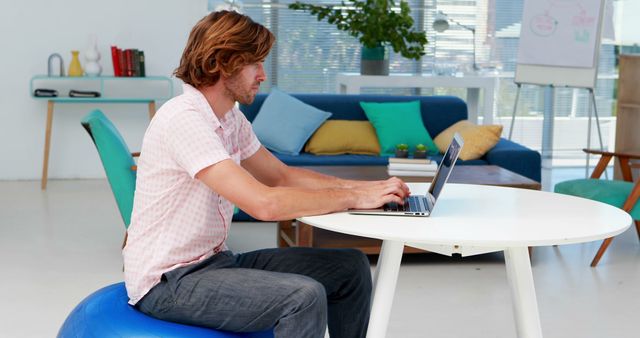 Man Working on Laptop Using Exercise Ball as Chair in Modern Office - Download Free Stock Images Pikwizard.com