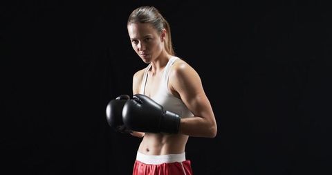 Female Boxer Showing Strength in Studio Pose with Boxing Gloves