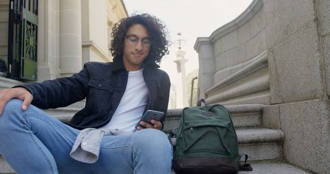Casual Young Adult Using Smartphone on City Steps