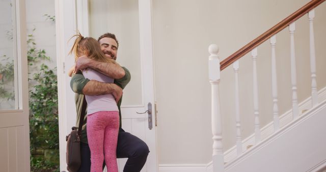 Father warmly hugs his daughter while greeting on his arrival at home. Emotion-filled moment captures love between father and child, making it ideal for themes of family, fatherhood, affection, and homecoming. Suitable for magazine articles, blogs, advertisements focusing on family relationships, parenting, and happiness at home.