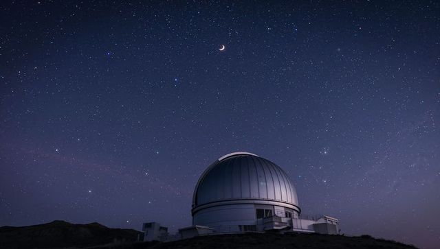 Stunning observatory dome beneath starry night with crescent moon