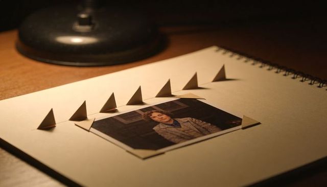 Vintage portrait secured with folded paper tabs on spiral sketchbook under warm desk lamp