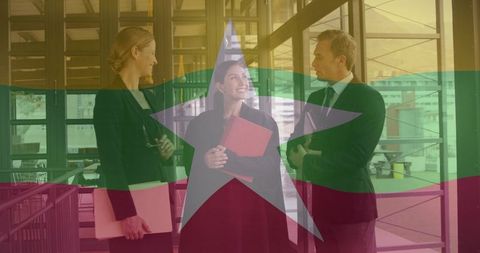 Discussing business strategy in glass atrium with flag overlay and team collaboration