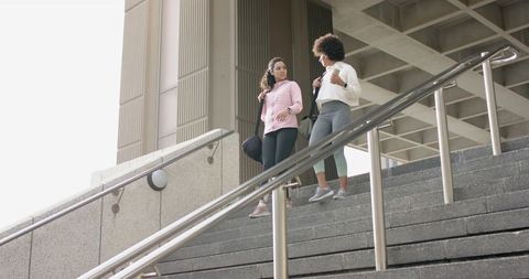 Female Students Walking Down University Stairs Carrying Backpacks and Duffel Bag