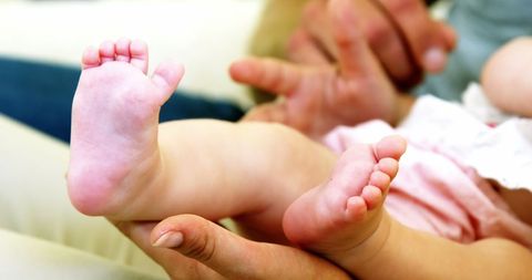 Close-up of parent cradling baby feet in bright light