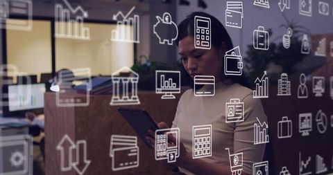 Businesswoman holding tablet analyzing financial data through glass partition with fintech icons