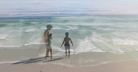 Ethereal double exposure family at beach mother in sundress with children facing horizon