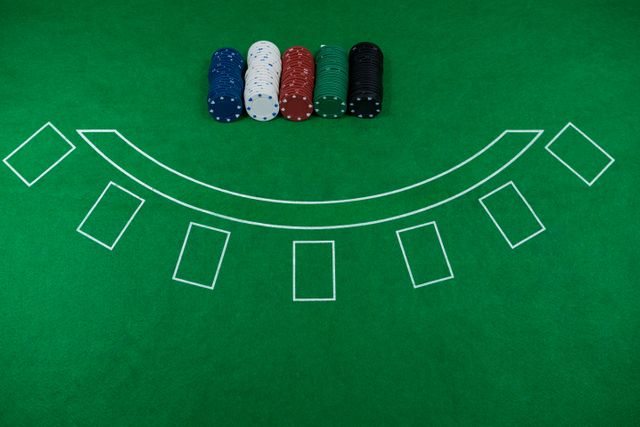 High angle view of poker chips neatly arranged on a green blackjack table. Ideal for use in articles or advertisements related to casinos, gambling, poker nights, and gaming events. Can also be used for illustrating casino game rules or strategies.