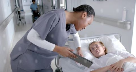 Nurse assists child patient with technology in hospital setting