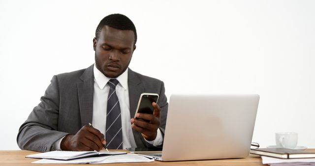 African American Businessman Working at Desk Using Smartphone and Laptop - Download Free Stock Images Pikwizard.com