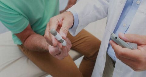 Doctor performing fingerprick blood glucose test on patient using lancet and glucometer